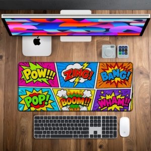 Comic Pow Pop Desk Mat on a wooden desk with monitor, keyboard and mouse